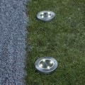 Solarne oprawy ogrodowe LED wpuszczane w trawnik z okrągłą obudową i zintegrowanymi diodami, emitujące punktowe światło jako oświetlenie ścieżki i ogrodu.