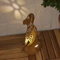 Solarna lampa ogrodowa LED w kształcie psa z dekoracyjnym wycinanym wzorem, ustawiona na drewnianym tarasie. Ozdoba z podświetleniem tworząca efekt wzoru na ścianie, dekoracja do ogrodu, na taras lub balkon.