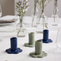 Porcelanowe świeczniki Bloom w niebieskim i zielonym kolorze, rozmieszczone na stole w jasnej, minimalistycznej aranżacji.