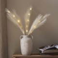 Dekoracyjne pióra LED w kolorze ecru z ciepłym światłem, umieszczone w wazonie na drewnianej konsoli w jasnym wnętrzu.