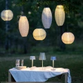 Solarne lampy stołowe LED ustawione na stole w ogrodowej aranżacji, tworzące nastrojowe oświetlenie.