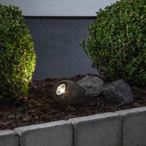 Solarny reflektor ogrodowy LED w formie kamienia oświetlający rośliny w rabacie, dekoracyjne oświetlenie zewnętrzne do ogrodu.
