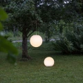 Solarna lampa LED w formie kuli zawieszona na gałęzi oraz stojąca lampa kulista na trawie, dekoracyjne oświetlenie ogrodowe z ciepłym światłem do różnych aranżacji.