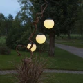 Solarne lampy ogrodowe LED w kształcie kul zawieszone na ozdobnej gałęzi, emitują ciepłe światło i tworzą nastrojowe oświetlenie przestrzeni zewnętrznej.