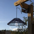Nowoczesna lampa solarna z czarnym kloszem zawieszona przy pergoli, subtelnie oświetlająca przestrzeń wokół.
