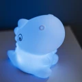 Lampka nocna dinozaur emitująca chłodne niebieskie światło, tworząca spokojny nastrój w wieczornym wnętrzu.