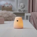 Lampka nocna miś świecąca ciepłym, pomarańczowym światłem, tworząca przytulną atmosferę w sypialni lub pokoju dziecka.