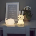 Lampka nocna króliczek i lampka w kształcie wieloryba ustawione na stoliku, tworzące przyjemny klimat i delikatne oświetlenie wieczorne.