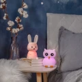 Lampki nocne w kształcie króliczka i sowy ustawione na stoliku, emitujące delikatne, kolorowe światło i tworzące przytulny klimat.