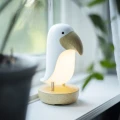 Lampka nocna ptaszek ustawiona na parapecie, subtelnie rozjaśnia przestrzeń i stanowi stylowy element dekoracyjny.