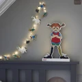 Girlanda świetlna Pippi zawieszona nad łóżkiem obok sylwetki bohaterki, tworzy spójną, bajkową aranżację i przytulnie rozświetla przestrzeń.
