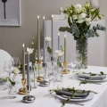 Eleganckie świece LED w różnych wysokościach na stole, doskonale uzupełniają odświętną aranżację z kwiatami i szkłem.