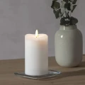 Dwie świece LED FLAMME białe 14 cm z realistycznym płomieniem, ustawione obok białego wazonu