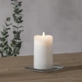 Świeca LED FLAMME 14 cm ustawiona przy liściastej gałęzi, biała ceramiczna podstawa