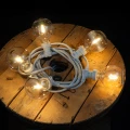 Girlanda świetlna z żarówkami LED G95 1W filament o ciepłej barwie 2700K na białym przewodzie. Plastikowe klosze odporne na uszkodzenia, dekoracyjne oświetlenie do ogrodu, tarasu i iluminacji miejskich.