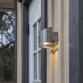 Kinkiet solarny z czujnikiem ruchu zamontowany przy drzwiach wejściowych, emituje ciepłe światło LED i subtelnie podkreśla elewację budynku.
