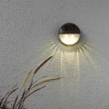 Lampa solarna LED zamontowana na ścianie, tworząca dekoracyjny wzór światła i podkreślająca fakturę elewacji.