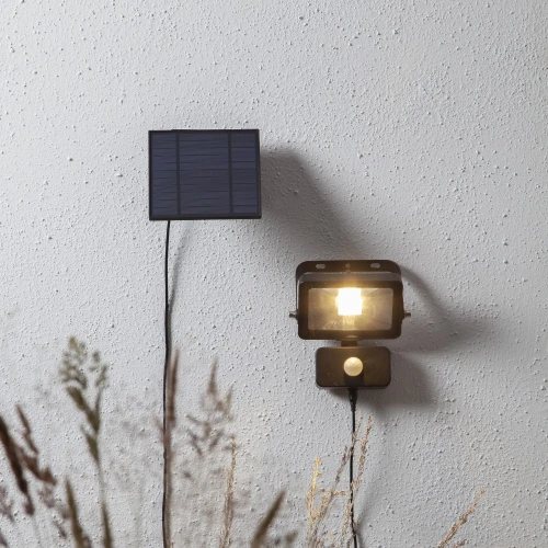 Solarny reflektor LED z czujnikiem ruchu zamontowany na ścianie praktyczne oświetlenie zewnętrzne do ogrodu lub elewacji.