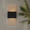 Solarny kinkiet LED na jasnej ścianie emituje ciepłe światło w górę i w dół tworząc przyjemny efekt oświetlenia.