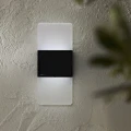 Solarny kinkiet LED na jasnej elewacji emituje chłodniejsze światło w górę i w dół podkreślając nowoczesny charakter przestrzeni.