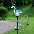 Ozdobna lampa solarna paw na paliku, z dekoracyjnym ogonem i szklaną kulą, idealna do trawnika lub ścieżki w ogrodzie, wprowadzająca lekki, elegancki akcent.