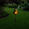 Dekoracyjna lampa solarna na szpikulcu z efektem płomienia i ciepłą kulą LED, umieszczona na trawniku. Subtelne światło dodaje przestrzeni elegancji i sprawia, że ogród zyskuje wyjątkowy charakter po zmroku.