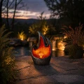 Dekoracyjna lampa solarna LED w formie płomienia ustawiona na kamiennej powierzchni w ogrodzie. Ciepłe światło tworzy przytulny nastrój i subtelnie podkreśla wieczorną aranżację przestrzeni.