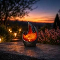 Nastrojowa lampa solarna LED w formie płomienia na tle zachodu słońca. Ciepła barwa światła buduje przyjemną atmosferę i stanowi elegancki akcent w ogrodzie lub na tarasie.