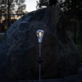 Solarna lampa ogrodowa LED w kształcie żarówki świecąca przy kamieniu po zmroku, nowoczesne oświetlenie dekoracyjne do ogrodu i ścieżek.