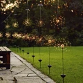 Lampki solarne imitujące sztuczne ognie przy ścieżce ogrodowej. Dekoracyjne solar firework tworzą klimatyczne oświetlenie tarasu, trawnika i ogrodu po zmroku.