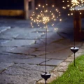 Dekoracyjne lampki w kształcie fajerwerków przy ogrodowej alejce. Solarna lampa LED typu firework zapewnia efektowne oświetlenie ścieżek i rabat.