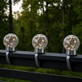 Trzy solarne lampy LED w formie szklanych kul z efektem spękanego szkła zamontowane na poręczy balkonu, nowoczesne oświetlenie dekoracyjne na taras i do ogrodu z ciepłym światłem.
