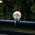 Solarna dekoracja LED w kształcie szklanej kuli z efektem spękanego szkła zamocowana na poręczy balkonu, emitująca ciepłe światło, nowoczesne oświetlenie ogrodowe na taras i balkon.