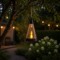 Dekoracyjny lampion solarny LED z efektem świecy zawieszony na drzewie w ogrodzie, zapewniający nastrojowe oświetlenie podczas wieczornego relaksu na świeżym powietrzu.
