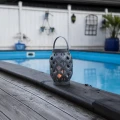 Dekoracyjny lampion solarny LED przy basenie na drewnianym tarasie.