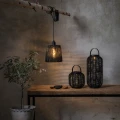 Lampiony solarne LED oraz wisząca lampa dekoracyjna w klimatycznej aranżacji z drewnianym stołem i roślinami.