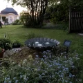 Solarne oświetlenie LED rozświetlające niewielki zbiornik wodny w ogrodzie.