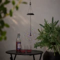 Solarna dekoracja ogrodowa Sztuczne Ognie LED FIREWORK® zawieszona nad stolikiem. Wielokolorowe diody tworzą efekt świetlnego fajerwerku w otoczeniu roślin i dekoracji tarasowych.