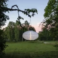 Owalny lampion solarny LED zawieszony na gałęzi na tle zieleni. Subtelne światło podkreśla dekoracyjny charakter przestrzeni po zmroku.