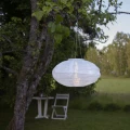 Solarny lampion LED z białego poliestru zawieszony na gałęzi drzewa. Subtelne światło i spokojna aranżacja tworzą przytulny klimat w ogrodzie.
