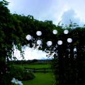 Świecąca girlanda solarna z białymi lampionami rozświetlająca pergolę po zmroku. Delikatne światło podkreśla charakter ogrodu i tworzy przyjemną atmosferę wieczorem.