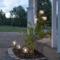 Zestaw solarnych lamp kulistych LED wykorzystany jako dekoracja rabaty i pergoli. Świecące kule rozmieszczone przy roślinach podkreślają przytulny charakter ogrodu po zmroku.