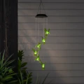 Solarna dekoracja wisząca LED z kolibrami zawieszona przy tarasie. Zielone podświetlenie akrylowych ptaków tworzy efektowną ozdobę na tle jasnej ściany.