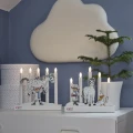 Dwa świeczniki LED z motywami Pippi Pończoszanki ustawione na białej komodzie w pokoju dziecięcym. W tle widoczne są roślina w doniczce oraz dekoracja w kształcie chmurki.