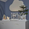 Trzy świeczniki LED z motywami Pippi Pończoszanki ustawione na białej komodzie. W tle widoczne są roślina w doniczce oraz dekoracja ścienna w kształcie chmurki.