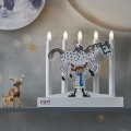 Świecznik LED z motywem Pippi Pończoszanki ustawiony na półce obok figurek jeleni. W tle widoczna jest dekoracyjna ściana z motywem gwiazd.