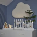 Trzy świecące scenki LED z motywami Pippi Pończoszanki ustawione na białej komodzie. Obok stoi doniczkowa choinka, a niebieską ścianę zdobi dekoracja w kształcie chmurki.
