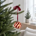 Szklana bombka LED z czerwonym spiralnym wzorem zawieszona na gałązce choinki na czerwonej satynowej wstążce. Jasne wnętrze podkreśla elegancki charakter świątecznej dekoracji.