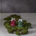 Dwa ceramiczne dzwonki LED z białymi kokardami w kolorze czerwonym i zielonym ustawiono na zielonym mchu, tworząc prostą, świąteczną aranżację.