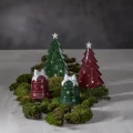 Cztery ceramiczne dekoracje świąteczne ustawione na mchu. Dwie choinki i dwa dzwonki w kolorach czerwonym oraz zielonym ozdobione są białymi detalami.